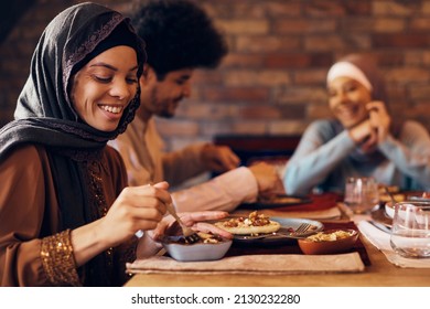 Happy Middle Eastern Woman Having Ramadan Iftar Meal With Her Family At Dining Table.