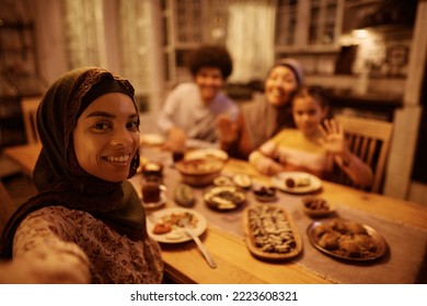 Happy Middle Eastern woman and her extended family taking selfie while having dinner during Ramadan. - Powered by Shutterstock