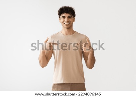 Happy Middle Eastern Young Man Pointing Fingers At Himself Smiling To Camera Standing Over White Background. Studio Shot Of Cheerful Arabic Guy In Casual Clothes. I Choose Myself Concept