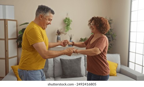 Happy middle-aged couple dancing together in a cozy living room of their home, sharing a moment of joy and love - Powered by Shutterstock