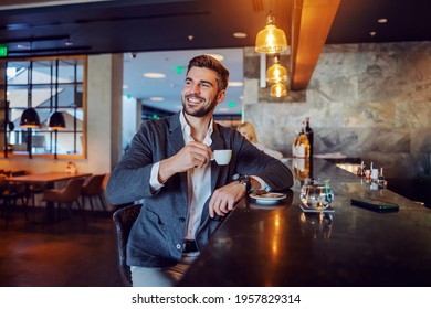 The happy middle-aged man in elegant formal clothes sitting in a hotel cafe and having his afternoon coffee. Coffee break, don't worry be happy, positive attitude and vibes - Powered by Shutterstock