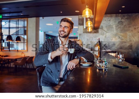 The happy middle-aged man in elegant formal clothes sitting in a hotel cafe and having his afternoon coffee. Coffee break, don't worry be happy, positive attitude and vibes