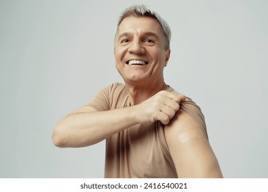 Happy middle-aged man showing his vaccination bandage, promoting health and prevention. - Powered by Shutterstock