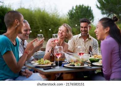 Happy middle-aged men and women toasting healthy food at farm house picnic - Life style concept with cheerful friends having fun together on afternoon relax time - Powered by Shutterstock