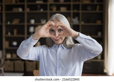 Happy Middle-aged Woman Join Fingers Makes Symbol Of Love Standing Alone In Living Room Looking At Camera, Heart Diseases Prevention, Cardio Check Up, Medical Insurance Cover For Older Citizen Concept