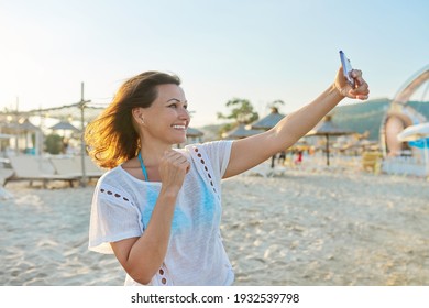 Happy Middle-aged Woman Talking On Smartphone Using Video Call, Female On Sandy Sea Beach. Summer, Vacation, Weekend In Nature, People Of Mature Age