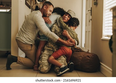 Happy military homecoming. Female soldier reuniting with her husband and children after serving in the army. Cheerful servicewoman embracing her family after returning home from deployment. - Powered by Shutterstock