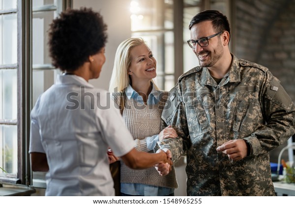 Happy military man shaking hands with female doctor while being with ...