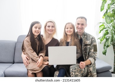 Happy Military Man Smiling And Hugging His Family While Using Laptop Indoors.