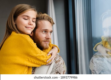 Happy Military Man Smiling While Carrying Her Daughter In His Hands Indoors