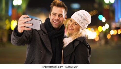 Happy Millenial Couple Having Fun Taking Selfies Together At Night In The City