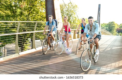 Happy Millenial Friends Having Fun Riding Bike At City Park - Friendship Concept With Young Millennial Students Biking Together On Bicycle Lane - Bright Late Afternoon Filter With Sunshine Halo