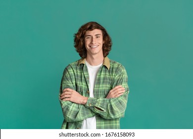 Happy Millenial Guy With Curly Hair Crossing His Arms On Turquoise Background