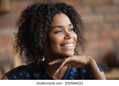 Happy Millennial African American Woman With Perfect Facial Skin And Teeth Enjoying Good Thoughts, Looking Away With Smile, Thinking Over Good News, Pondering On Future Vision. Close Up Portrait