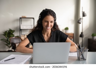 Happy Millennial Business Woman In Headset, Working At Laptop From Home, Making Video Call, Talking To Coworkers Online On Virtual Conference Meeting. Support Manager Speaking To Client, Smiling