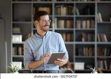 Happy millennial Caucasian man in glasses use tablet look in distance planning or visualizing future success. Smiling young male work on pad gadget, dreaming or thinking. Business vision concept. - Powered by Shutterstock