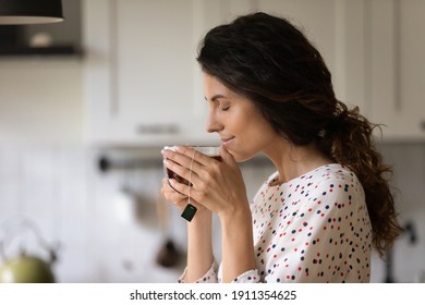 Happy Millennial Caucasian Woman Hold Mug Drink Enjoy Hot Black Tea In The Morning At Home. Calm Young Female Have Warm Beverage From Cup, Relax Rest On Weekend In Cozy Home. Hygge Concept.