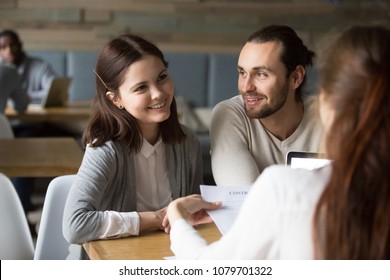 Happy Millennial Couple Planning To Sign Mortgage Contract Meeting Realtor, Smiling Clients Considering Real Estate Deal, Buying Insurance, Investing Money Being Consulted By Financial Advisor Broker