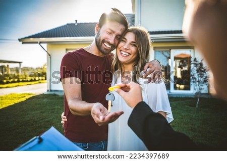 Happy millennial couple receiving keys from realtor, purchasing real estate - Family meeting with real estate agent - New house and real estate concept