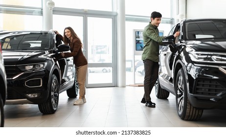 Happy Millennial Couple Selecting New Car, Buying Or Renting Automobile At Auto Dealership, Banner Design. Cheerful Young Family Choosing Vehicle Together At Automotive Showroom, Copy Space