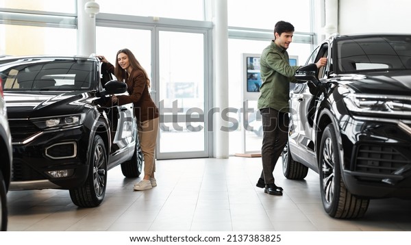 Happy\
millennial couple selecting new car, buying or renting automobile\
at auto dealership, banner design. Cheerful young family choosing\
vehicle together at automotive showroom, copy\
space
