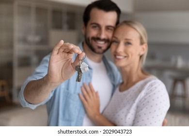 Happy Millennial Couple Showing Key From New House, Smiling At Camera. Property Buyers, Tenants Homeowners Celebrating Mortgage, Rent Apartment, Real Estate Purchase Deal . Close Up Of Hand