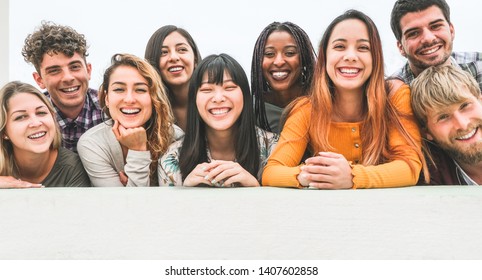 Happy millennial friends from diverse cultures and races having fun posing in front of smartphone camera - Youth and friendship concept - Young multiracial people smiling - Main focus on center faces - Shutterstock ID 1407602858