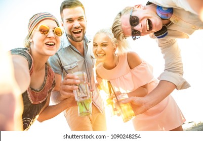 Happy millennial friends group taking selfie at fun beach party drinking cocktails at sunset - Summer joy and friendship concept with young people on vacation - Bright sunshine filtered color tones