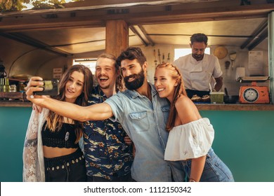 Happy millennial friends group taking selfie. Group of happy young people taking selfie with smartphone near a food truck. - Powered by Shutterstock