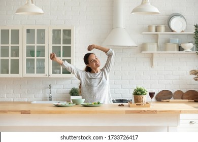 Happy Millennial Girl Preparing Healthy Breakfast Having Fun In Bright Modern Kitchen At Home, Overjoyed Young Woman Cooking In New House Or Apartment Feel Excited Moving Relocating To Own Dwelling