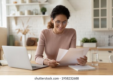Happy millennial hispanic lady review printed paper documents financial reports satisfied with good state of business low tax rate paid debt confirmation. Glad young female do paperwork read good news - Shutterstock ID 1958232688