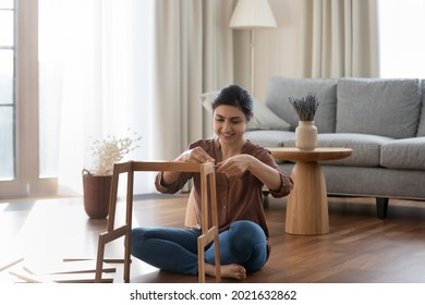 Happy millennial Indian female renter or tenant sit on floor in new house gather shelf. Smiling young ethnic woman put together make build piece of furniture settle in own home. Rental concept. - Shutterstock ID 2021632862