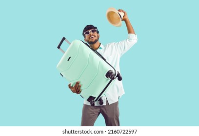 Happy Millennial Indian Guy Isolated On Blue Studio Background Hold Suitcase Excited About Summer Travel. Overjoyed Young Biracial Man Prepared For Summertime Vacation. Tourism Concept.