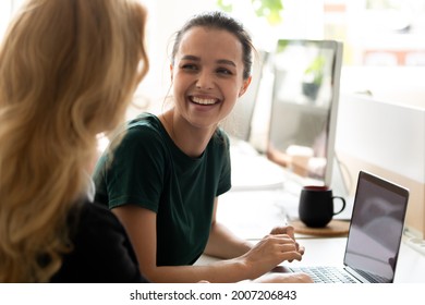 Happy millennial intern, student girl talking to teacher, consulting tutor, mentor at computer in training center, discussing new professional skills, smiling, laughing. Business education, internship