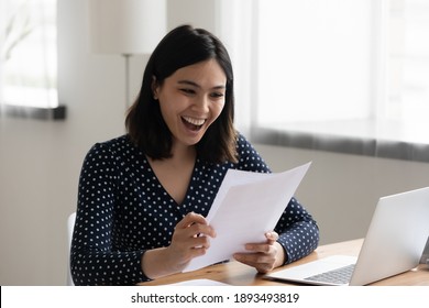 Happy Millennial Korean Asian Woman Reading Paper University Admission Notification, Feeling Excited Alone At Home. Euphoric Smiling Young Mixed Race Female Worker Getting Job Promotion Letter.