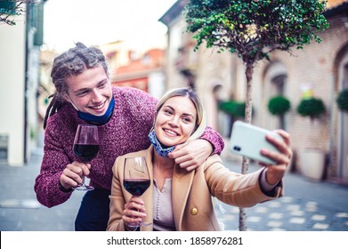 Happy Millennial Lovers Enjoying Lunch Together At Restaurant Patio - Young Couple In Love With Open Face Mask Taking Selfie At Outside Wine Bar - New Normal Lifestyle Concept