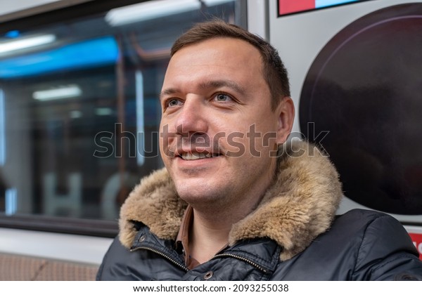 Happy millennial man moving on subway train. Sad\
casual guy moving to home while sitting at window and thinking.\
Travelling passenger\
concept.