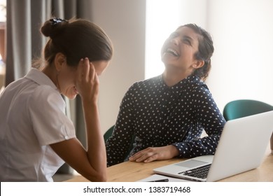 Happy millennial multiethnic women have fun sitting at office desk talking, smiling diverse female colleagues or employees laugh chatting at workplace, discuss ideas or gossip at work break - Shutterstock ID 1383719468