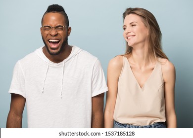 Happy millennial multiracial couple isolated on blue studio background laugh at funny joke together, overjoyed young multiethnic man and woman friends stand smiling having fun, humor concept - Powered by Shutterstock