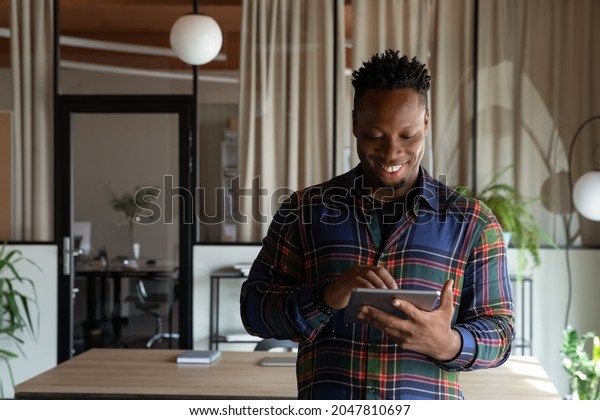 Happy\
millennial self employed professional using tablet in office. Young\
African American hipster guy, student, employee using virtual app,\
online service on pad computer, chatting,\
browsing