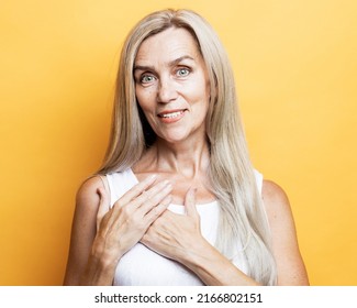 Happy Mindful Thankful Old Woman Holding Hands On Chest Smiling Isolated On Yellow Background Feeling No Stress, Gratitude, Mental Health Balance, Peace Of Mind Concept.