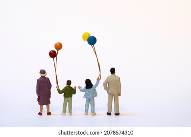 Happy miniature family with balloons, back view on white background