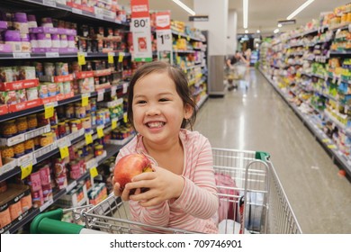 Happy Mixed Ethnic Asian Little Customer Girl Smiling And Sitting In A Trolley, Shopping Cart At Supermarket, Grocery Store