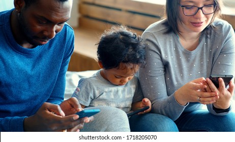 Happy Mixed Ethnicity Family Little African Dad Kid Son And Caucasian Mom Holding Phone Having Fun With Smartphone, Mother Father With Child Boy Looking At Cellphone Enjoy Using Mobile Apps At Home