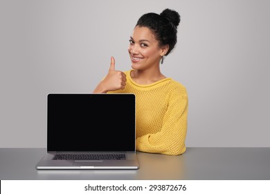 Happy mixed race african american - caucasian woman showing blank black laptop computer screen, looking at camera smiling, gesturing thumb up