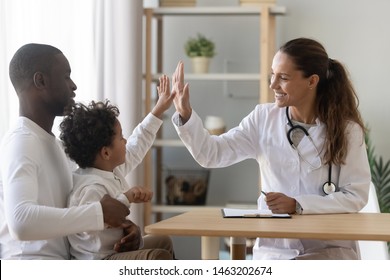 Happy mixed race african cute little child boy give high five to female doctor pediatrician welcome small kid patient and his dad at medical check up appointment, children medical health care concept
