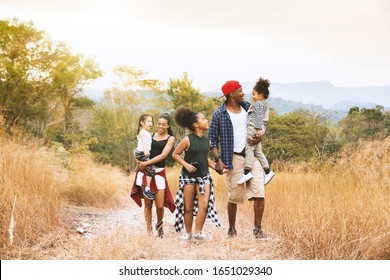 Happy Mixed Race Big Family With Father, Mother And Child Daughter Walking On Country Road. Travel Vacation Concept