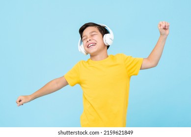 Happy mixed race boy listening to music on headphones and dancing in studio light blue isolated background - Powered by Shutterstock