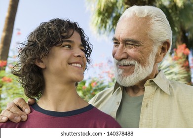 Happy mixed race boy looking at his senior grandfather outdoors
