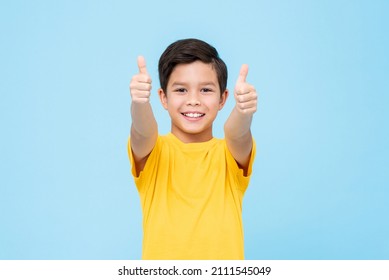 Happy mixed race boy in yellow t shirt smiling and looking at camera while showing thumbs up gesture in approval against blue background - Powered by Shutterstock